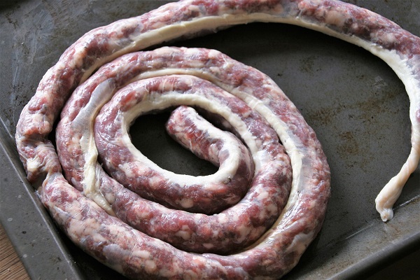 Den mit Rehfleisch gefüllten Naturdarm zu einer Schnecke aufdrehen
