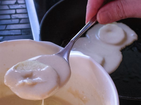 Apfelscheiben mit dem Teig zum braten aus der Schüssel nehmen