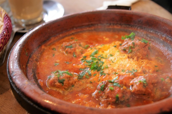 Abbildung ein marokkanischer Kochtopf mit Tomatensoße, Eiern und Hackfleischbällchen in einem Restaurant in Marrakesch