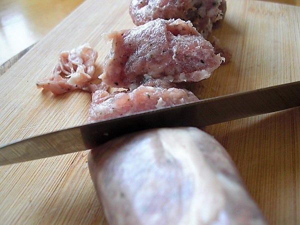 Foto Bratwurstbrät wird mit Messerrücken von der Haut getrennt