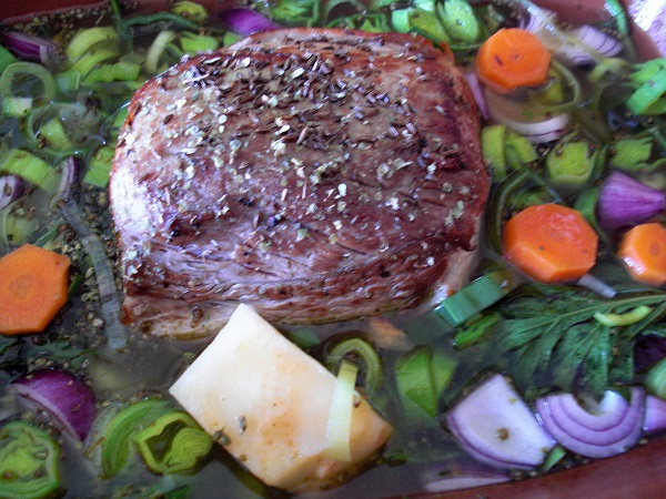 Schweinebraten mit Gemüse in einem Schmortopf geben