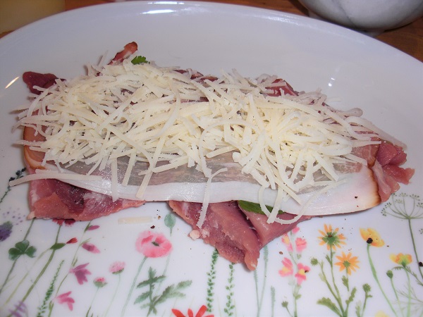 Foto Schweineroulade mit rohem Schinken und gehobeltem Manchego-Käse belegt