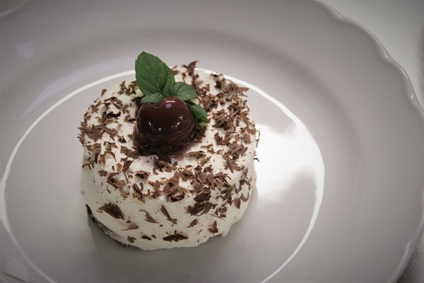 Foto kleines Törtchen einer echten Schwarzwälder Kirschtorte auf weißem Teller