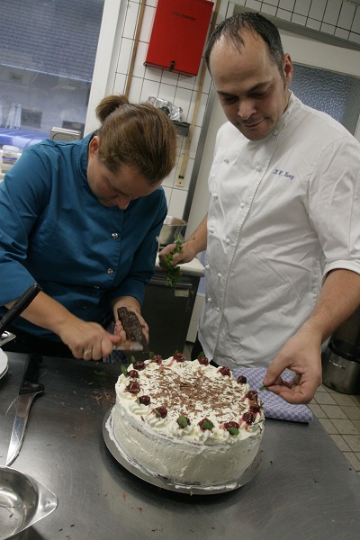 Foto Konditor und Konditorin garnieren eine echte Schwarzwälder Kirschtorte
