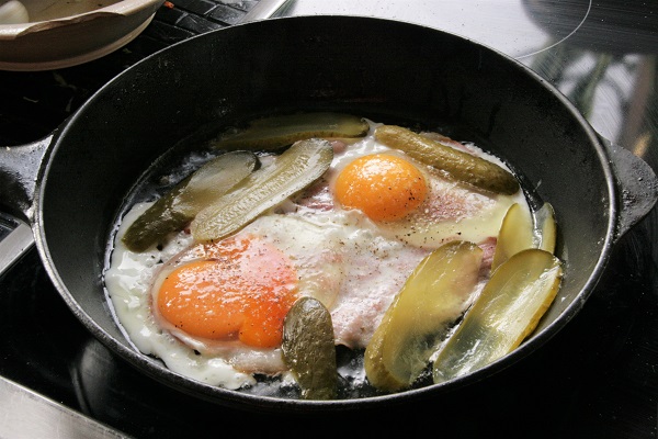 Foto Speck, Eier und Essiggurken werden in einer Pfanne angebraten