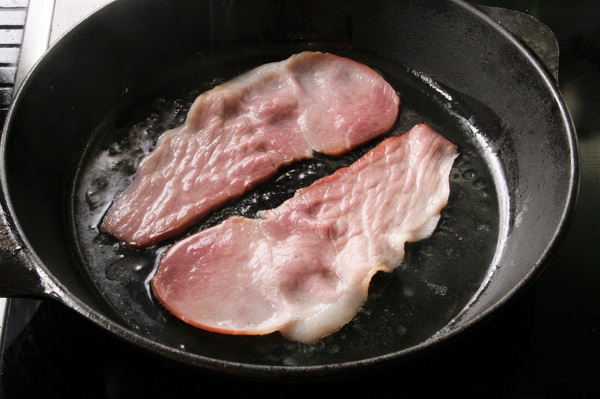 Foto zwei Scheiben Speck in einer Pfanne angebraten