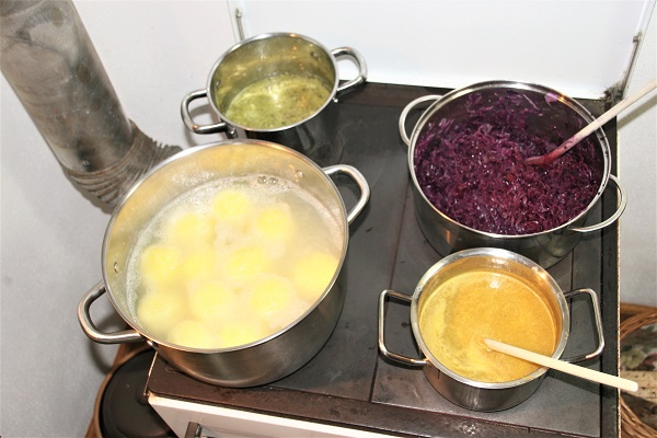 Foto Töpfe mit Klöße, Wirsing und Blaukraut auf einem Holzherd