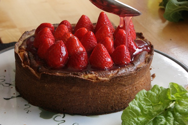 Käsekuchen mit Erdbeeren wird mit Tortenguss begossen