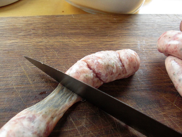 Bratwurstbrät wird mit Messerrücken aus der Haut gestrichen